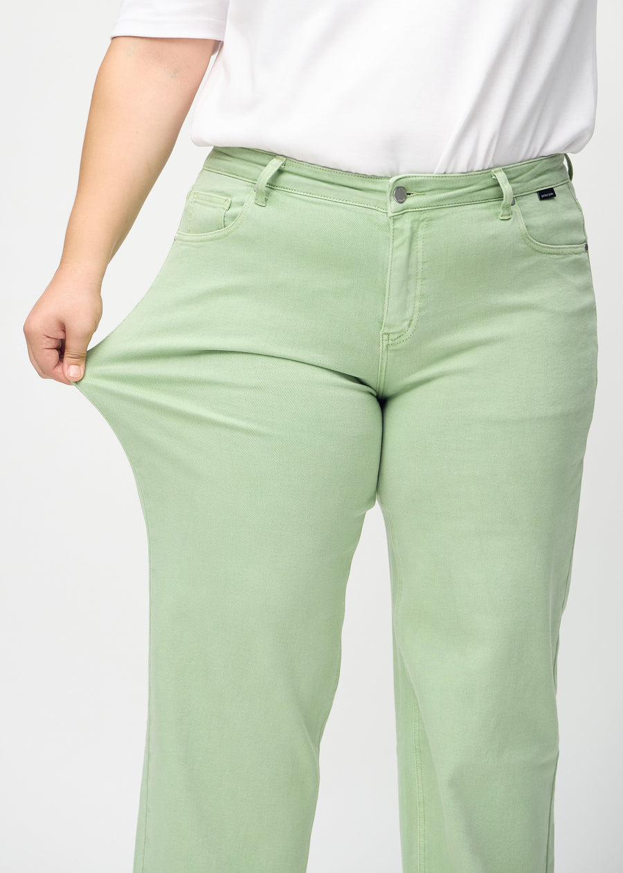 Plus-size model strækker jeansene ved låret for at vise stretch.