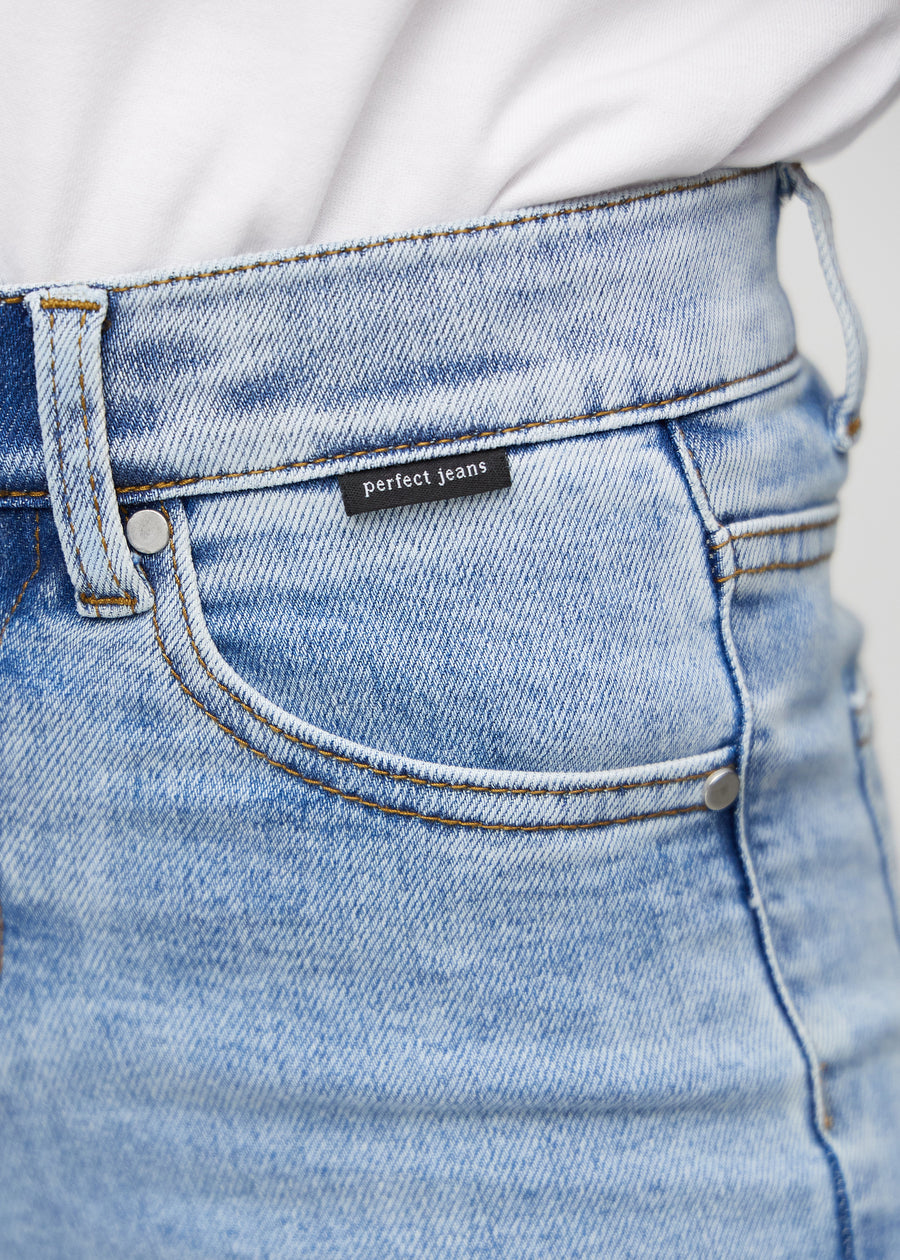 Close-up of light blue denim with Perfect Jeans logo label at the front pocket edge.
