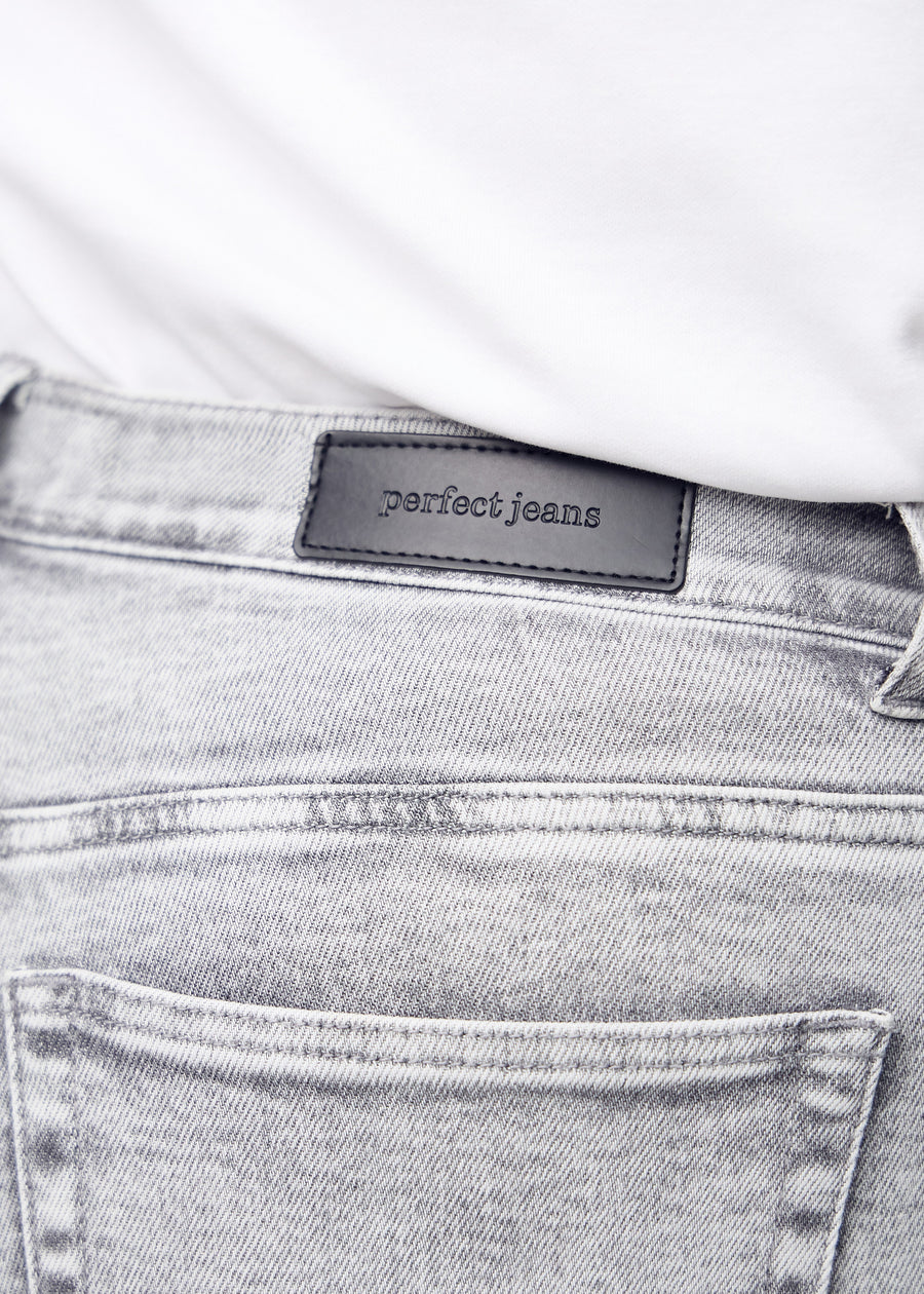 Nærbillede af lysegrå denim med Perfect Jeans læderpatch bagpå i taljen, på en plus-size model.