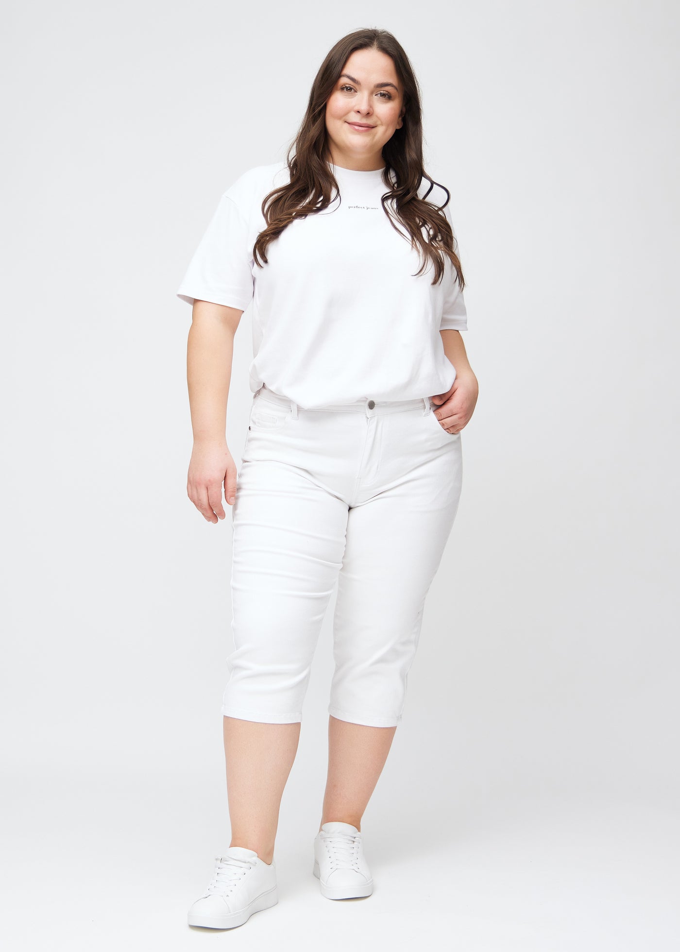 Fuldt billede af plus-size model i hvide slim capris.