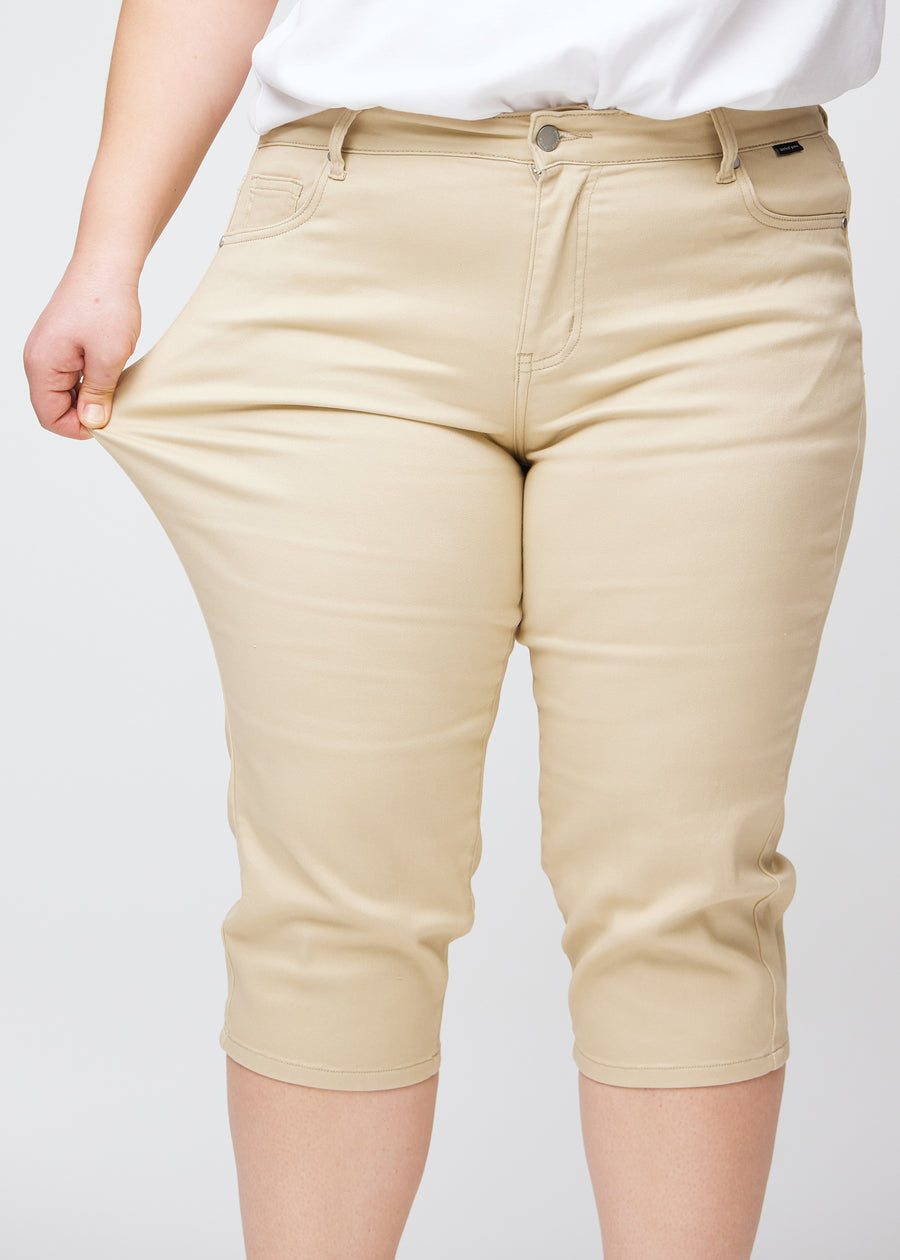 Plus-size model viser stretch ved at trække i caprisene ved låret – fokus på komfort og fleksibilitet.