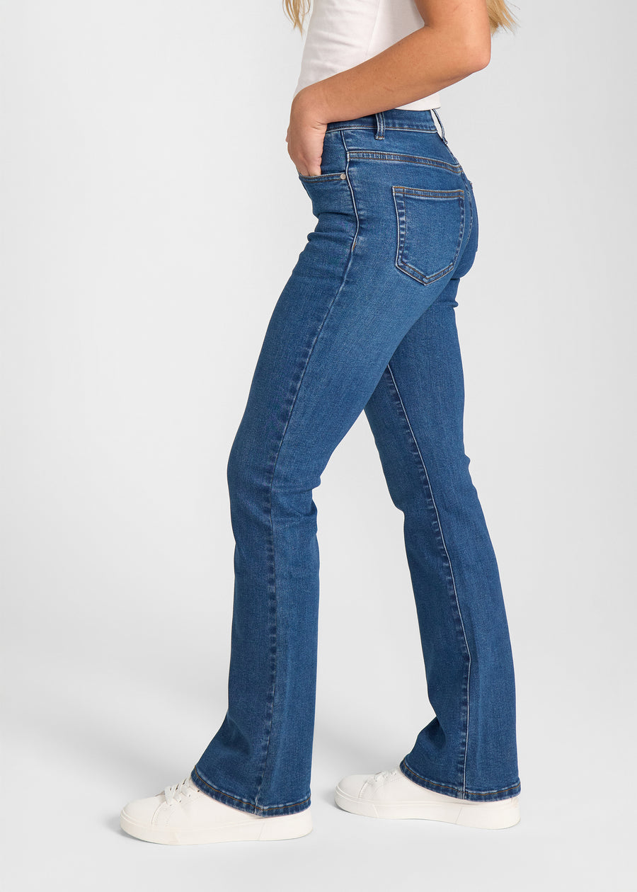 Mørkeblå denim bootcut jeans, modelnavn Oceans, som sidder tæt om hofter og lår med et let svaj fra knæet og ned, set fra siden på model.