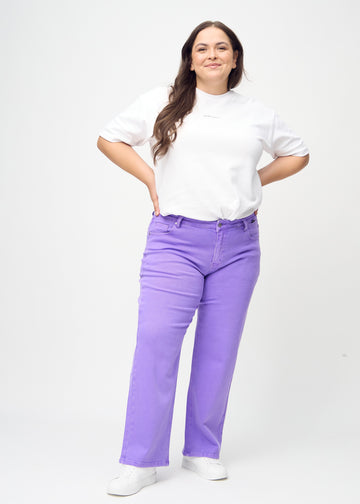 Plus-size model går ind i billedet, viser jeansene frem ved at strække i dem, dreje rundt, og derefter forlade billedet.