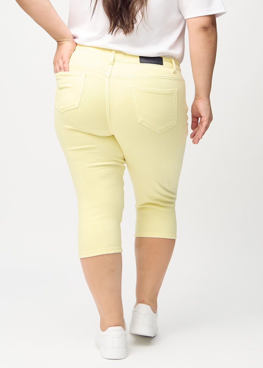 Lysegule skinny capris set bagfra på en plus-size model, så man kan se hele produktet.