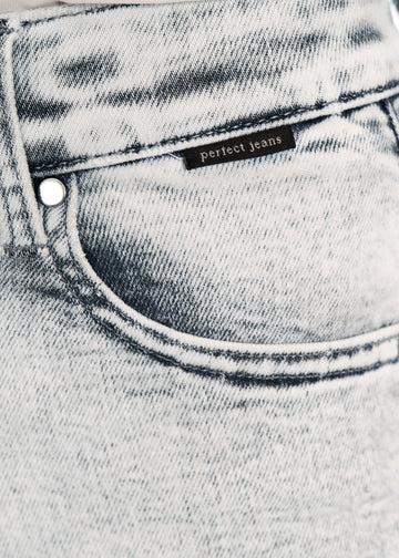 Nærbillede af lysegrå denim med Perfect Jeans logoetiket ved forlommekanten, på en plus-size model.