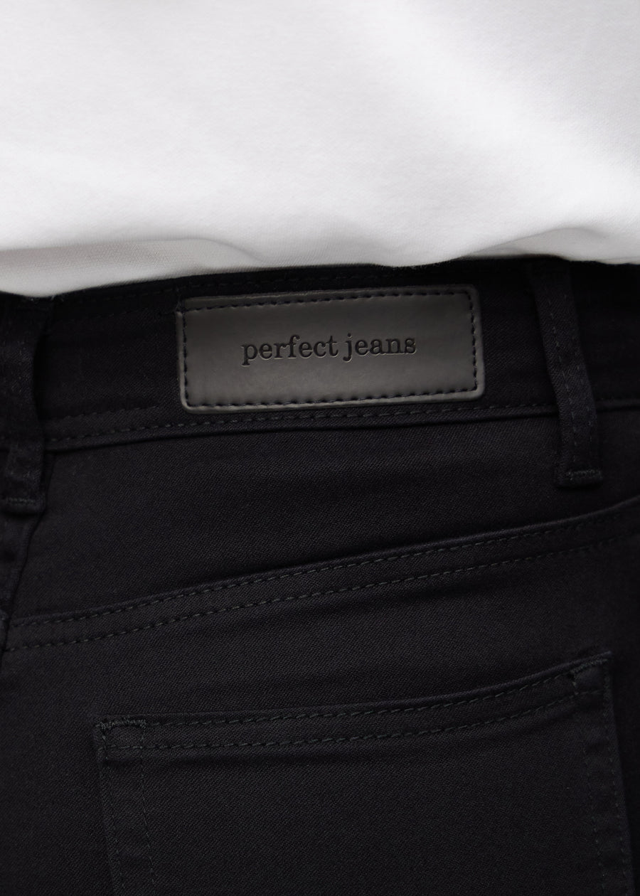 Nærbillede af sort jeansmateriale med Perfect Jeans læderpatch bagpå i taljen.