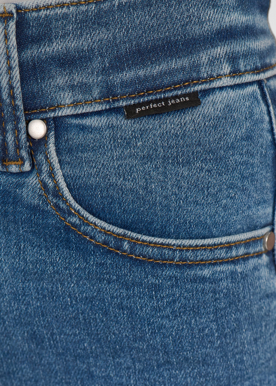 Nærbillede af mørkeblå denim med Perfect Jeans logoetiket ved forlommekanten.