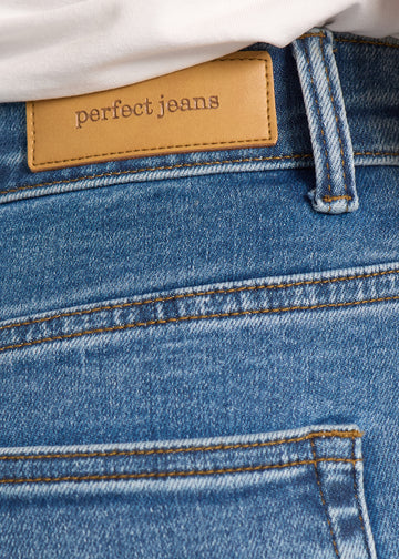 Nærbillede af mørkeblå denim med Perfect Jeans læderpatch bagpå i taljen.