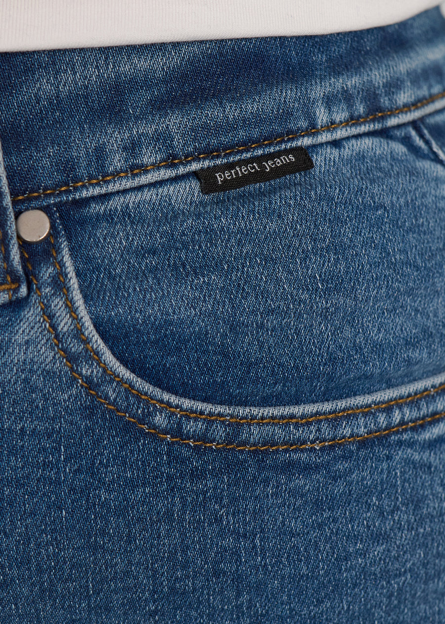 Nærbillede af mørkeblå denim med Perfect Jeans logoetiket ved forlommekanten, på en plus-size model.