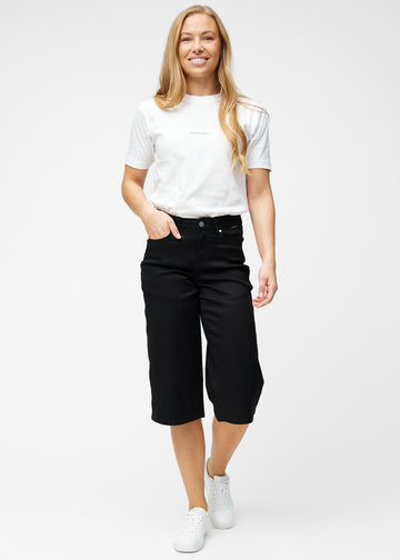 Fuldt billede af model i løse, sorte capris i farven Ravens, der går til lige under knæet.