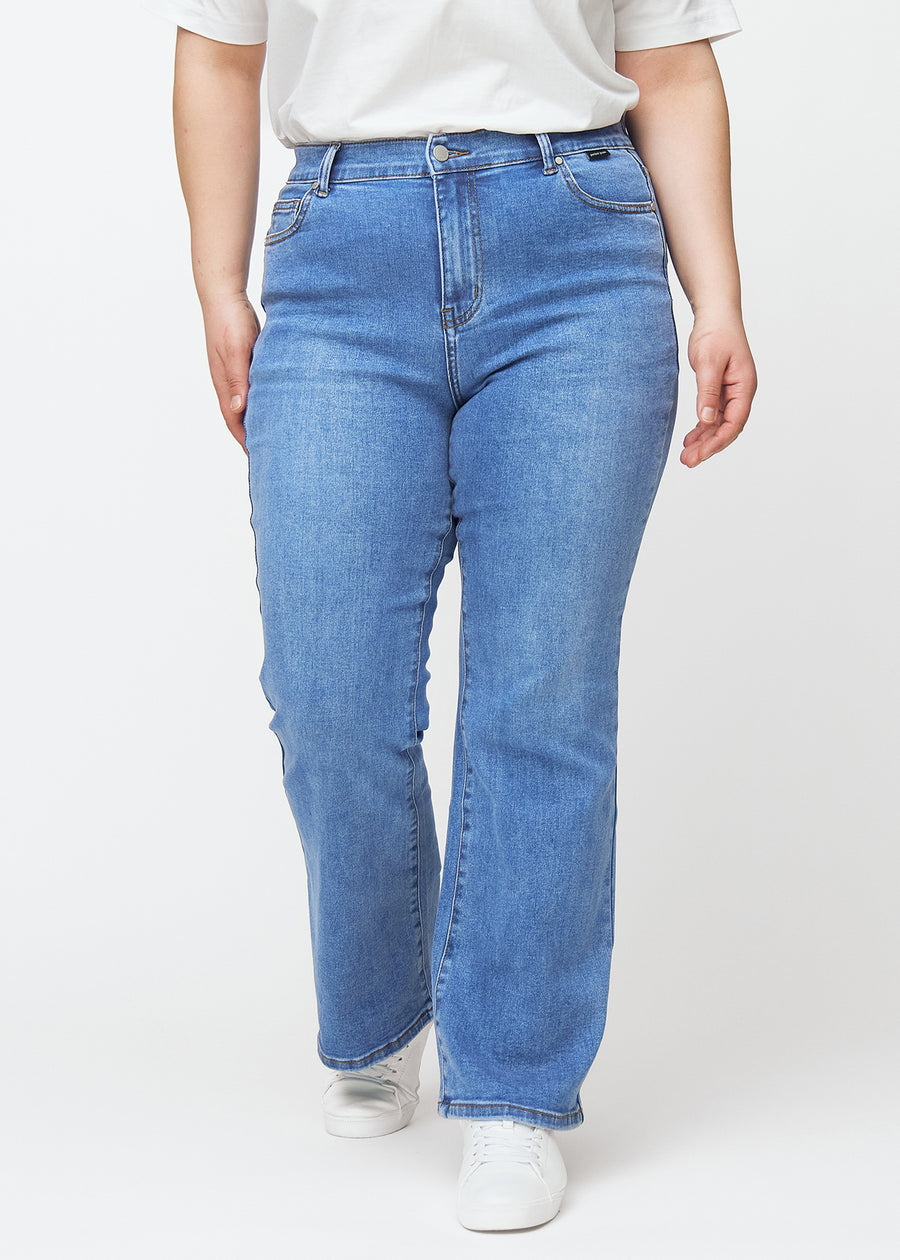 Blå mid-rise bootcut jeans i denimfarven Rivers, modelnavn Ravens, som sidder tæt fra hofte til lår og har et let svaj forneden, på en plus-size model, set forfra.