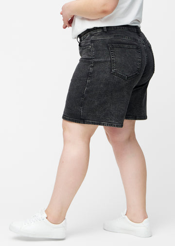 Løse, mørkegrå denim shorts i farven Shadows set fra siden på plus-size model, hvor den brede pasform og længden til lige over knæet er synlig.
