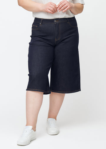 Deep dark blue denim capris for women in the colour Midnights with a loose fit seen from the front on a plus-size model.