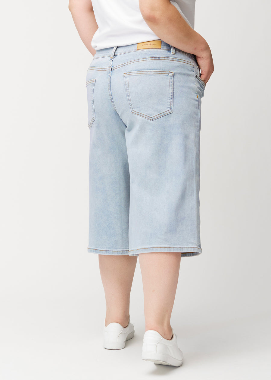 Løse, lyseblå denim capris i farven Waves set bagfra på plus-size model, så pasform og længde kan ses.