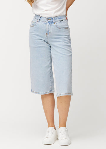 Løse, lyseblå denim capris i farven Waves, der sidder til ved hoften og falder løst ned over lårene til lige under knæet, set forfra.