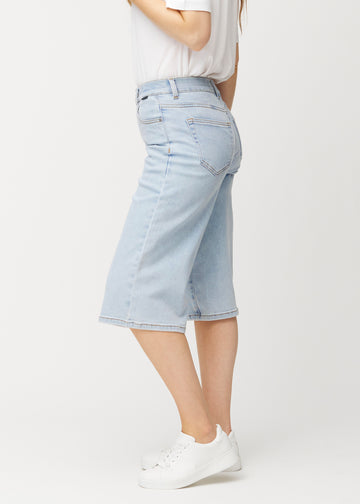 Løse, lyseblå denim capris i farven Waves set fra siden på model, hvor den brede pasform og længden til lige under knæet er synlig.