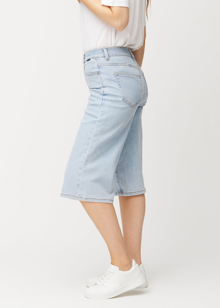 Løse, lyseblå denim capris i farven Waves set fra siden på model, hvor den brede pasform og længden til lige under knæet er synlig.