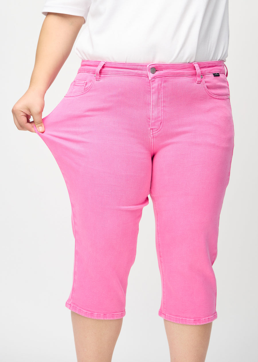 The plus-size model stretches the capris at the thigh to show the stretch.
