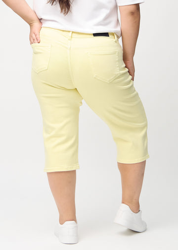 Light yellow regular capris seen from the back on a plus-size model, so the entire product can be seen.