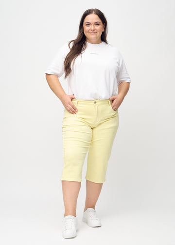 Light yellow regular capris seen from the back close up on a plus-size model to show details.