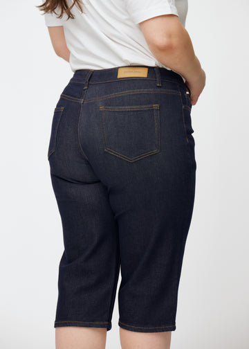 Deep dark blue denim capris for women in the colour Midnights seen from the back in close-up on a plus-size model.
