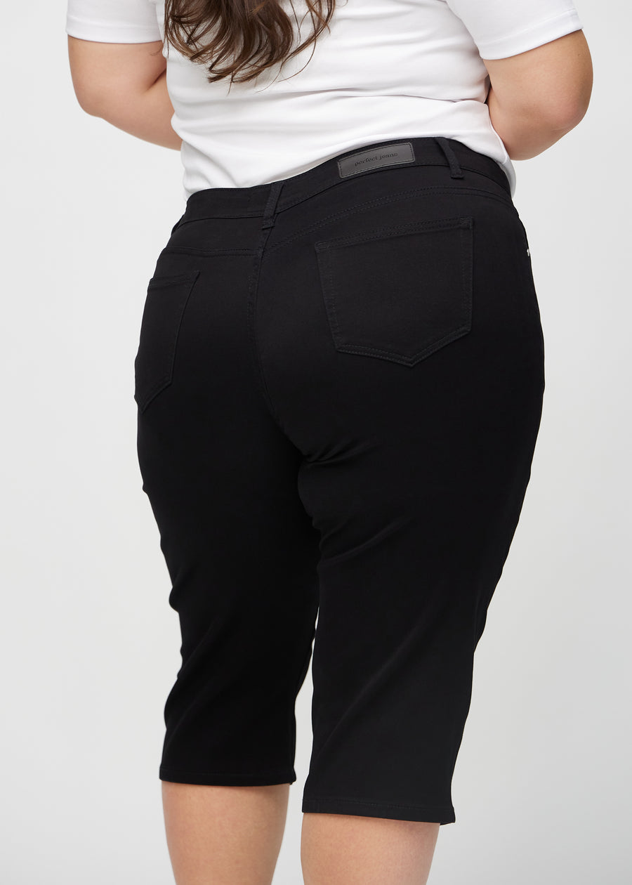 Black regular capris seen from the back close up on a plus-size model to show details.