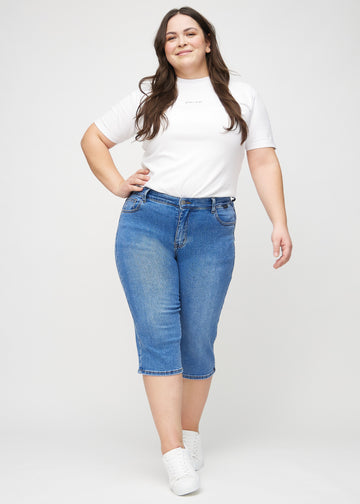 Full image of a plus-size model wearing denim regular capris.
