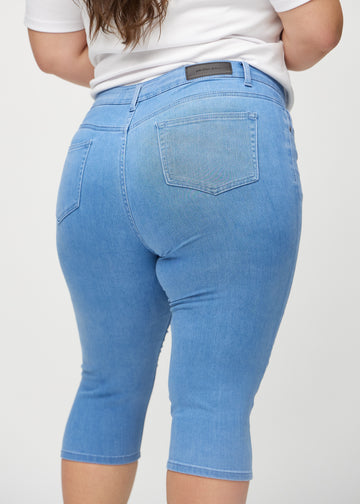 Blue skinny capris seen from the back close up on a plus-size model to show details.