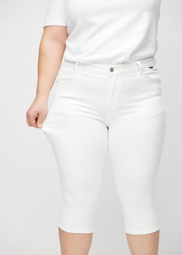 The plus-size model stretches the capris at the thigh to show the stretch.