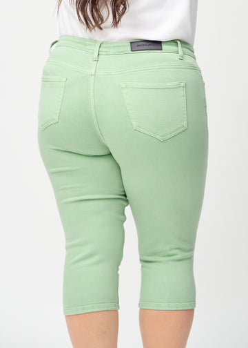 Skinny capris for women in pastel green fabric, color Mints. Close-up from behind on a plus-size model, highlighting pockets and stitching.