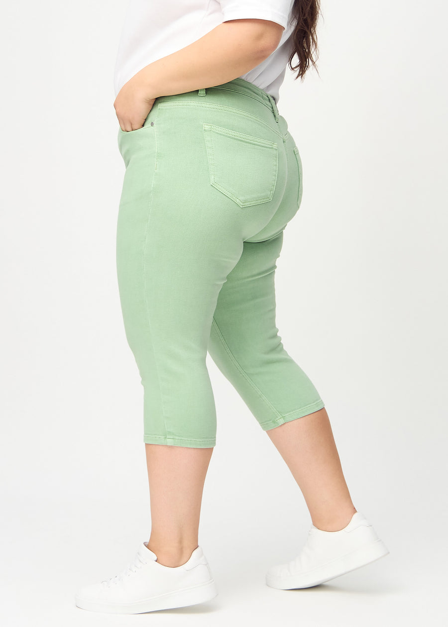 Skinny capris for women in pastel green fabric, color Mints. Side view on a plus-size model, showing the fitted cut.