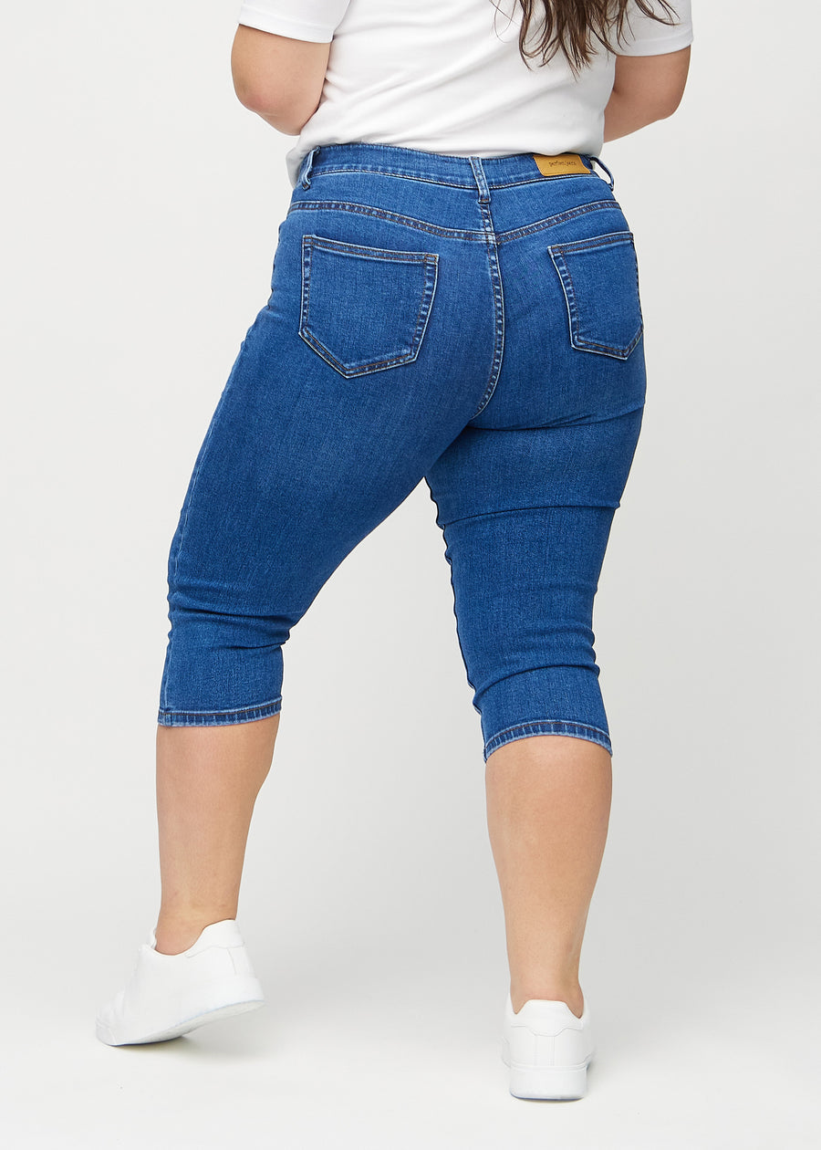 Dark denim skinny capris seen from the back on a plus-size model, so the entire product can be seen.