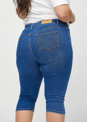 Dark denim skinny capris seen from the back close up on a plus-size model to show details.