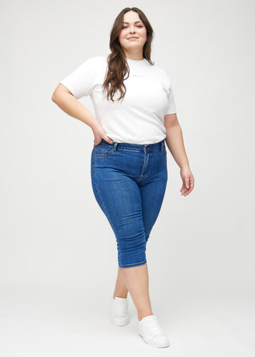 Full image of a plus-size model in dark denim skinny capris.