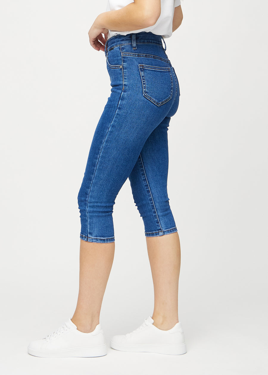 Dark denim skinny capris seen from the side on a model.