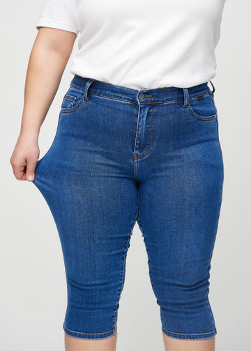 The plus-size model stretches the capris at the thigh to show the stretch.