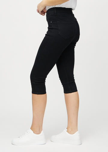 Black skinny capris seen from the side on a model.