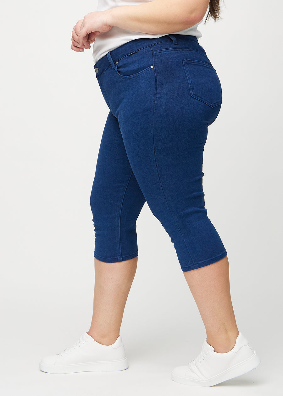 Dark blue skinny capris seen from the side on a plus-size model.
