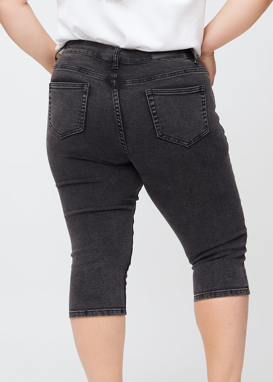 Dark grey denim skinny capris seen from the back up close on a plus-size model to show details.