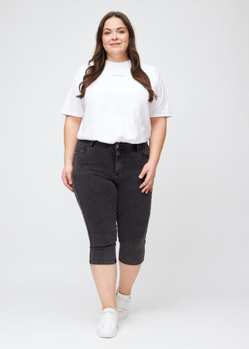 Full image of a plus-size model in dark grey denim skinny capris.