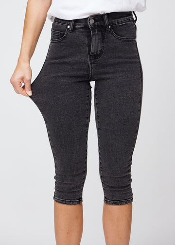 The model stretches the capris at the thigh to show the stretch.