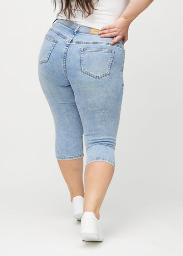 Light denim skinny capris viewed from the back on a plus-size model, so the entire product can be seen.