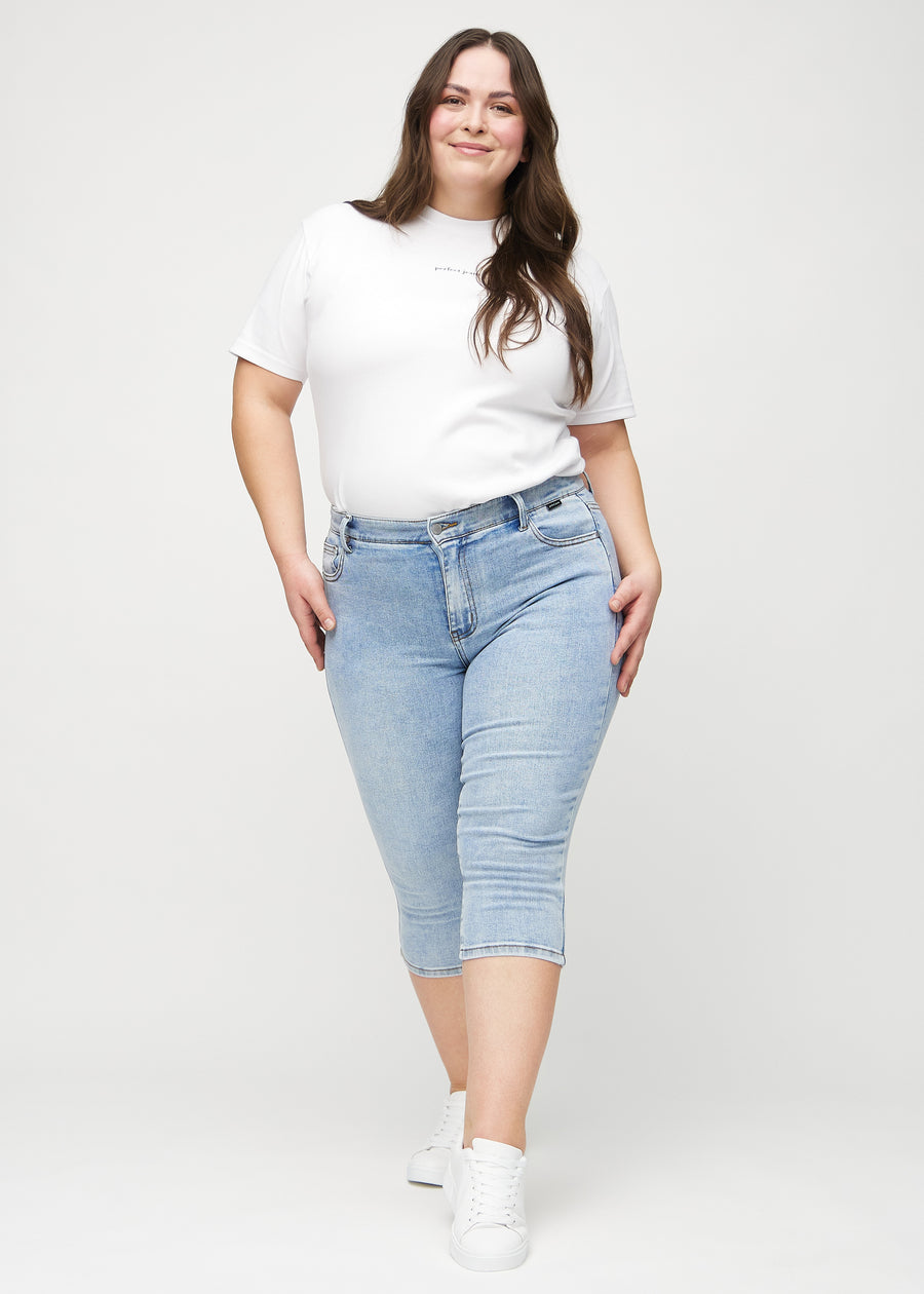 Full image of a plus-size model in light denim skinny capris.