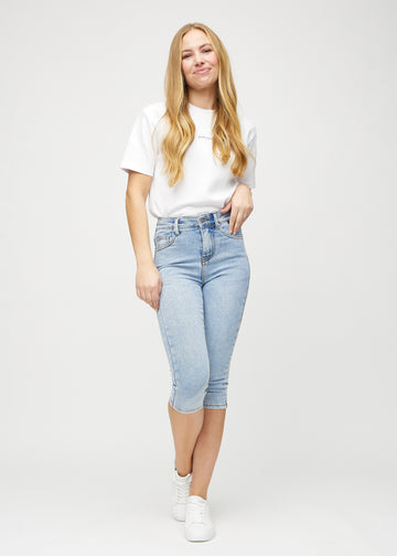 Full image of model in light denim skinny capris.