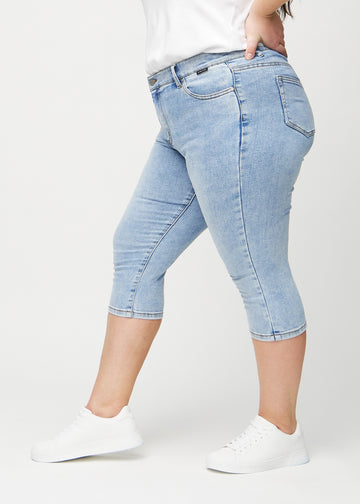 Light denim skinny capris viewed from the side on a plus-size model.