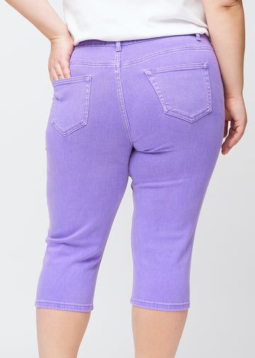 Slim capris for women in pastel purple jeans fabric, color Lavenders. Close-up from behind on a plus-size model, highlighting the back pockets and stitching.