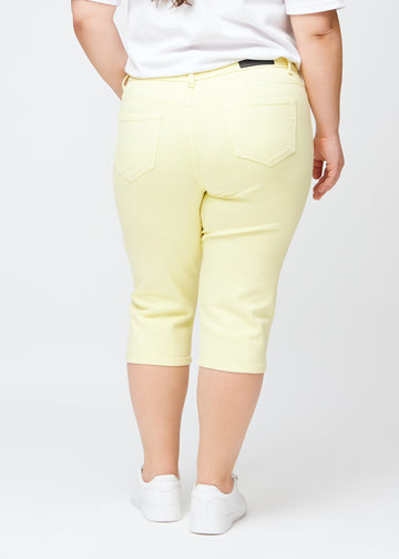 Light yellow slim capris seen from the back on a plus-size model, clear image of the full product and pockets.