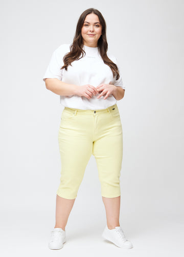 Full image of plus-size model in light yellow slim capris.
