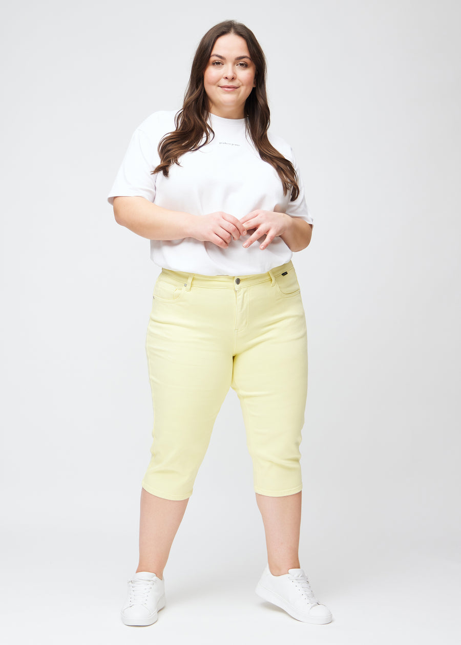 Full image of plus-size model in light yellow slim capris.
