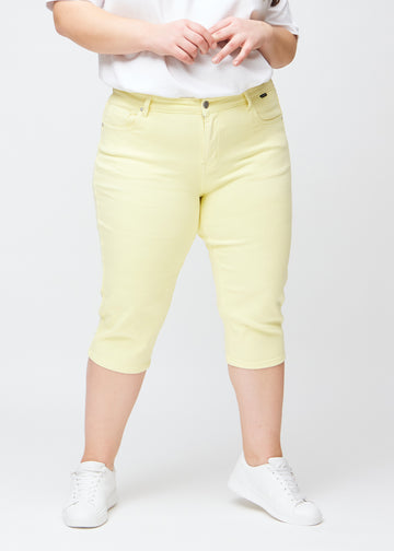Light yellow slim capris, colour Lemonades, with a close-fitting fit and length just below the knee, seen from the front on a plus-size model.
